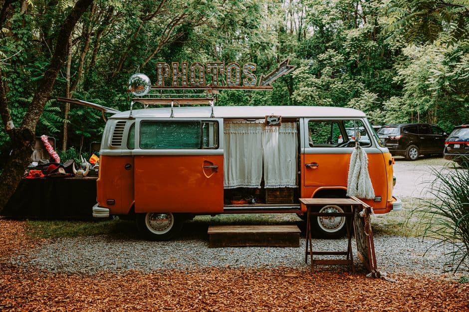 Charming vintage Volkswagen van photobooth in a lush outdoor setting, perfect for events.