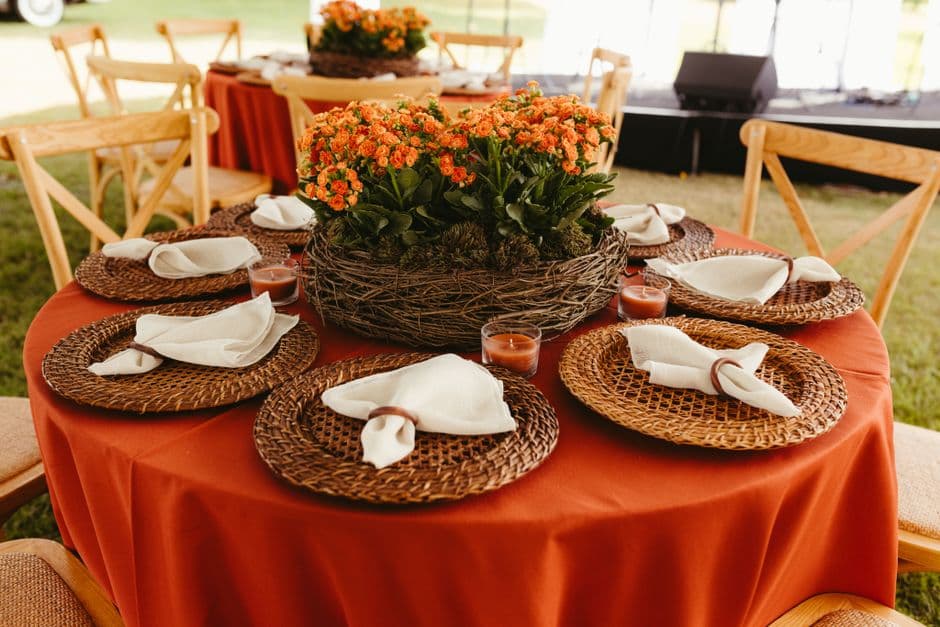 Charming wedding table setting with orange floral centerpiece and rustic decor, perfect for an outdoor event.