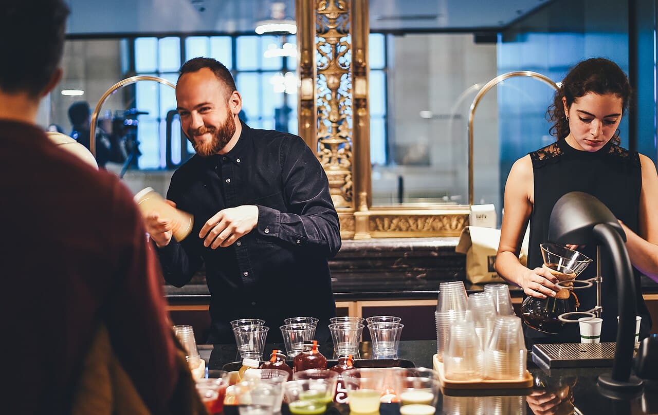 Bartenders serving cocktails at a bar
